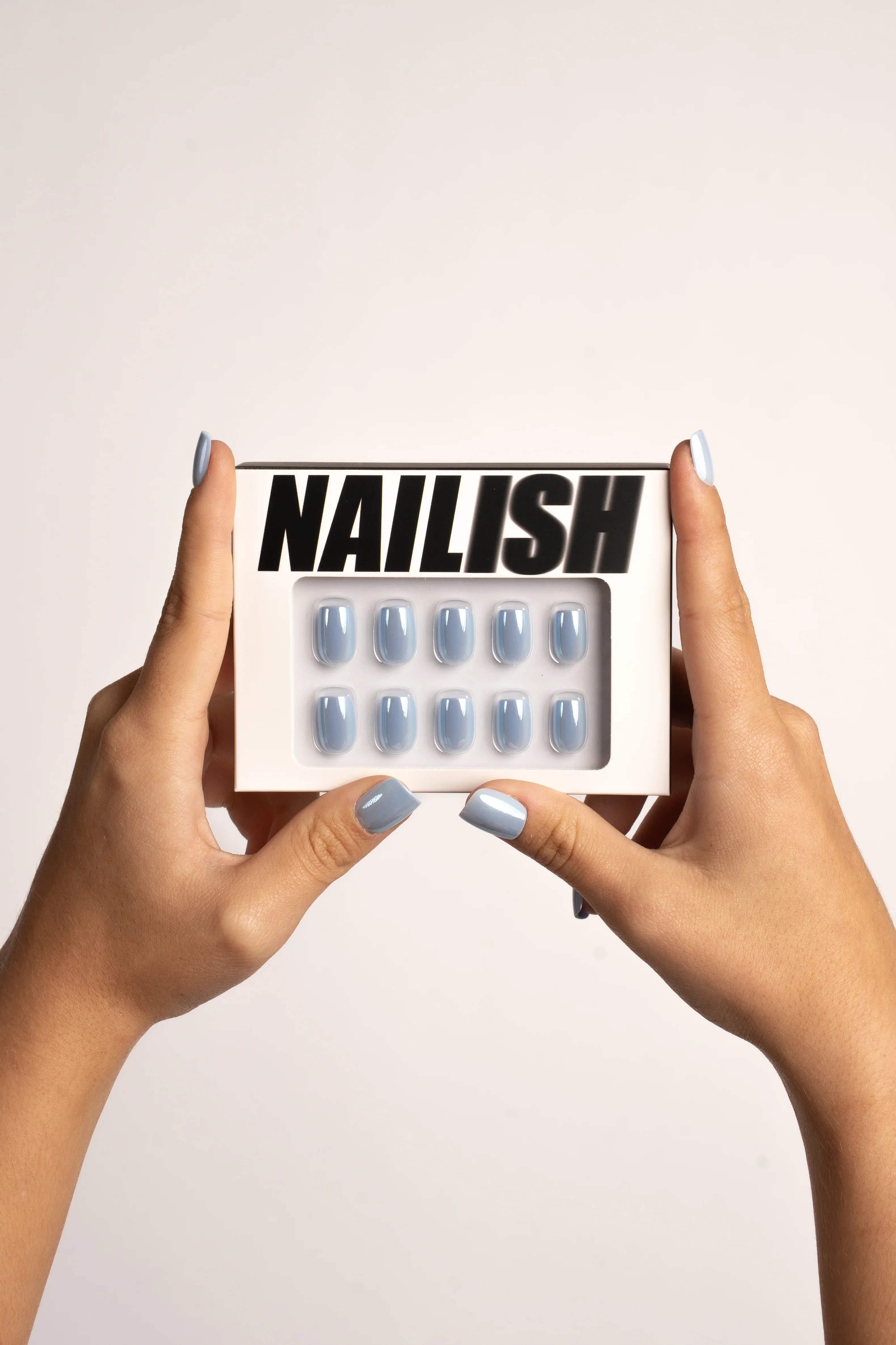 Hände mit hellblauen Press On Nägeln halten Box mit glänzenden, FlexiGel Kunstnägeln in Pastellblau
