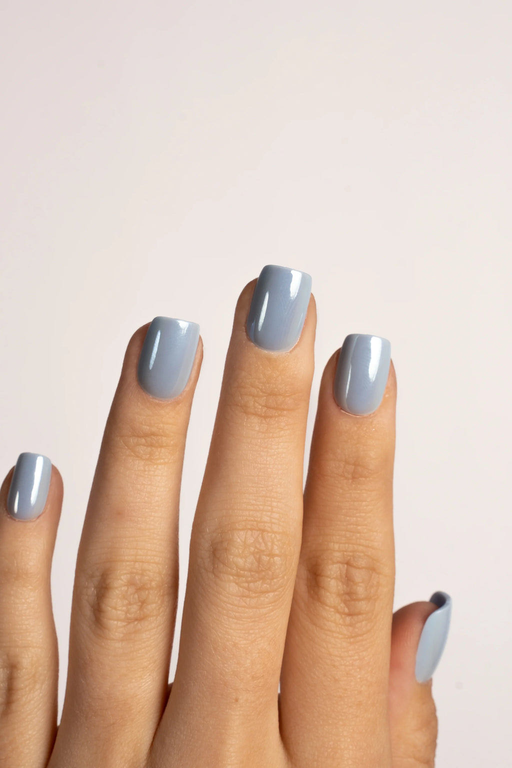 Hand mit glänzenden hellblauen FlexiGel Press On Nails, Nahaufnahme, neutrale Kulisse