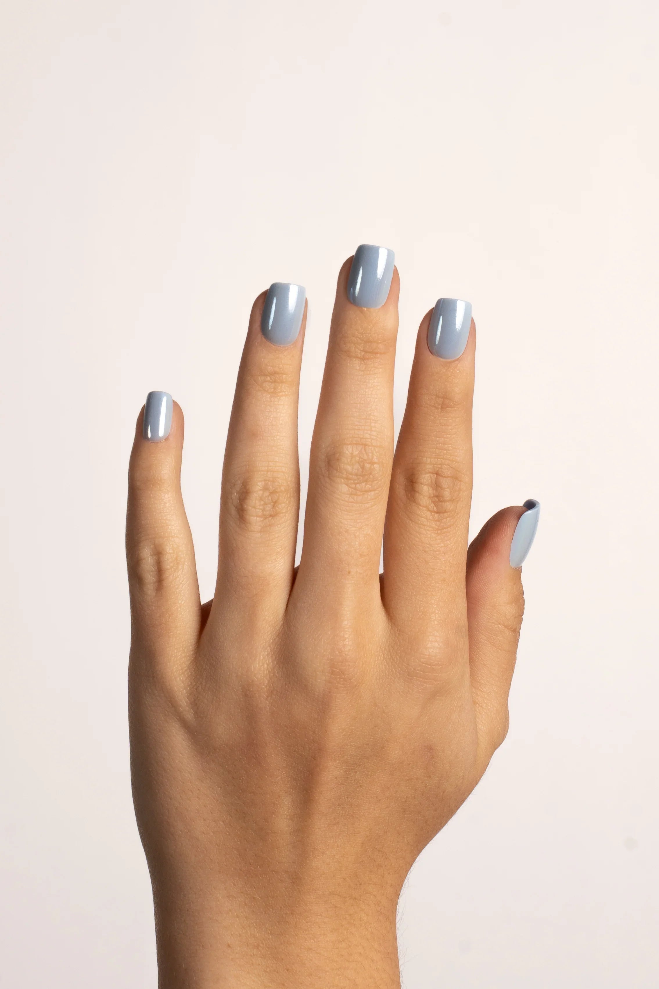 Hand mit hellblauen FlexiGel Press On Nails, glänzend und natürlich geformt
