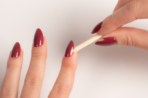Hand mit dunkelroten FlexiGel Press-On Nails – Anwendung mit Rosenholzstäbchen von Nailish