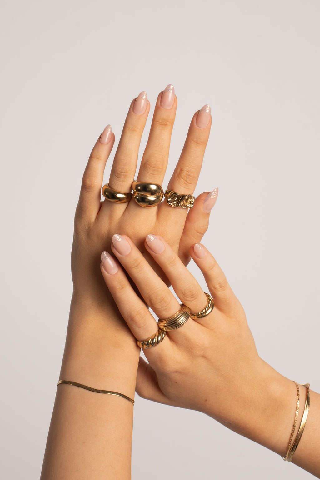Hände mit FlexiGel Press-On Nails in Golden Lines – Nude mit goldenen Linien und Goldschmuck von Nailish
