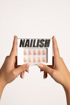 Hände halten Nailish Verpackung mit Vanilla Fade FlexiGel Press-On Nails – Nude Farbverlauf in Mandelform