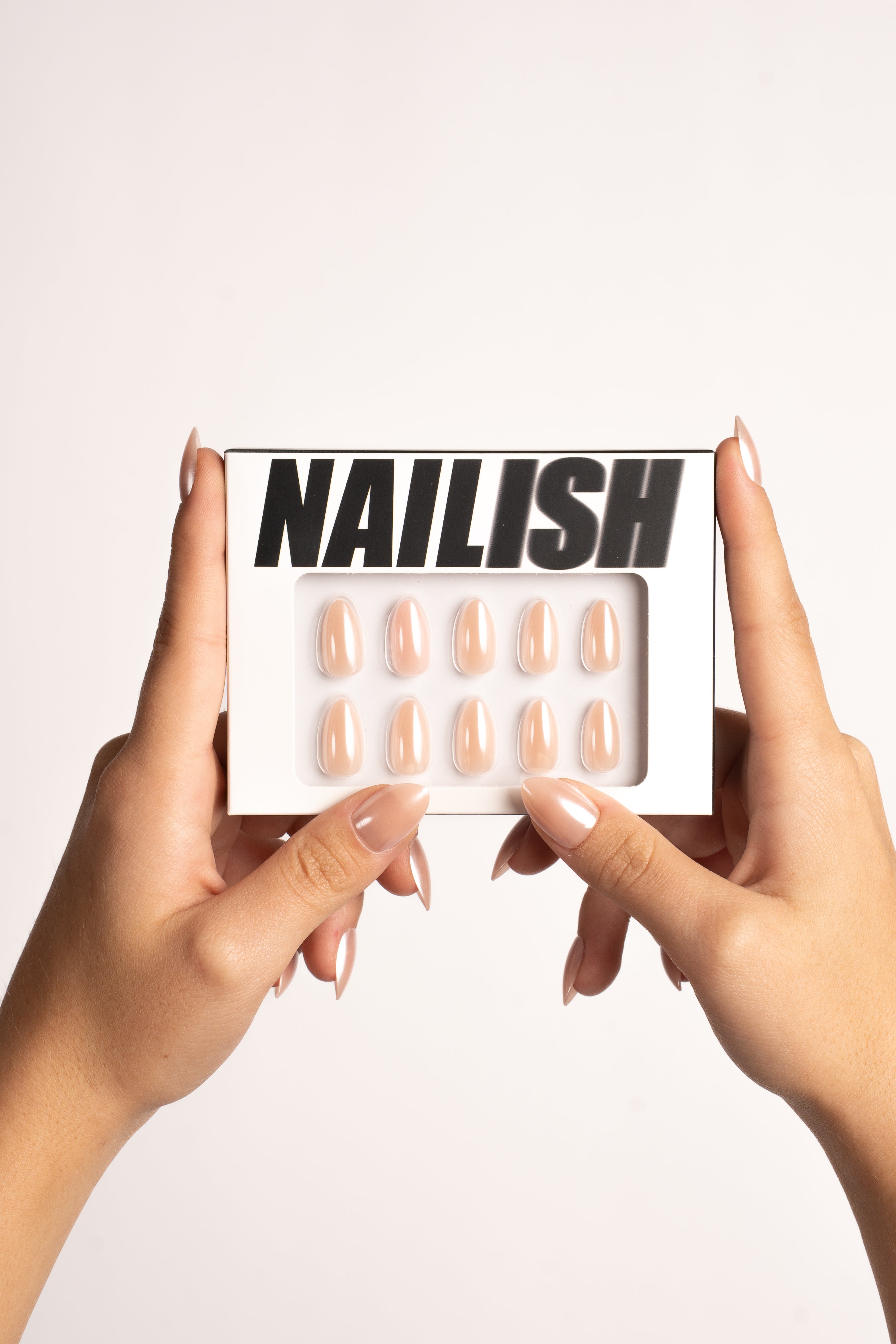 Hände halten Nailish Verpackung mit Vanilla Glaze Soft Gel Press-On Nails in cremigem Nude